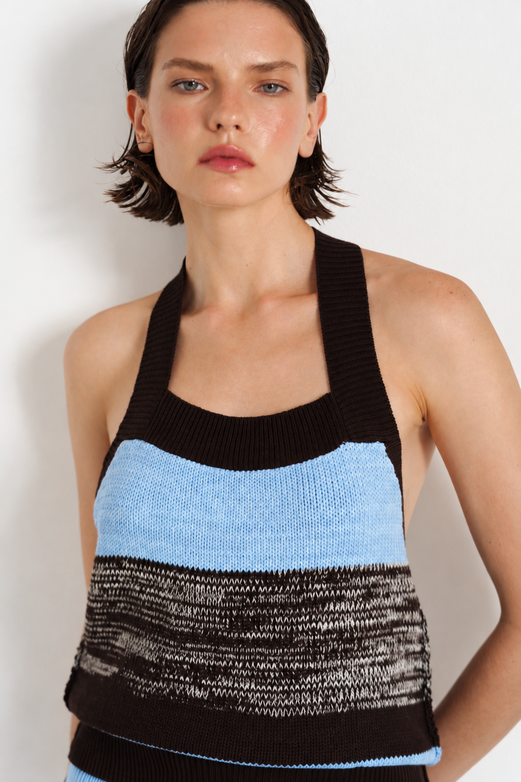 A model wearing a ribbed knit halter top with horizontal stripes in black, light blue, and a marled black-and-white pattern.