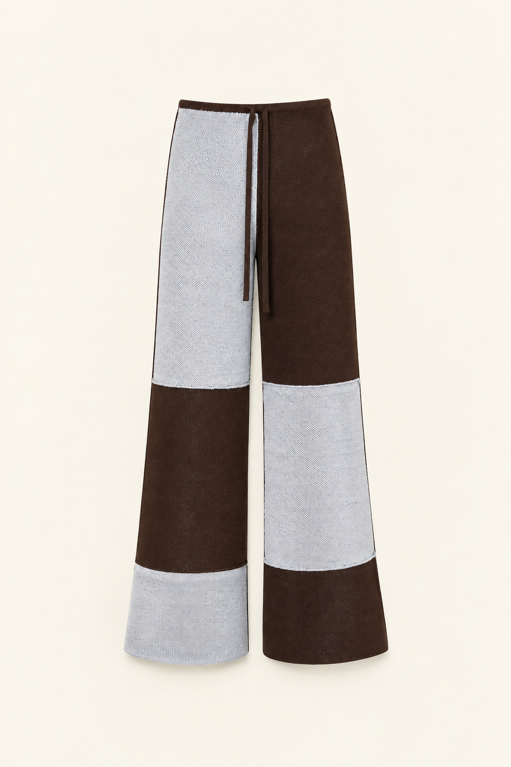 Colorblock wide-leg cropped pants in brown and light gray, featuring a drawstring waistband, shown against a solid cream background.
